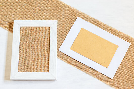 Zero waste eco friendly blank frame for card greeting or party invitation or more purpose. White wooden picture frame, textured burlap fabric, craft envilope with copy space.