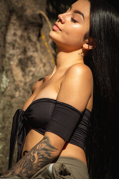 Mujer joven bronceada delgada sexy con ropa de color negro posando en un entorno de naturaleza. retrato de moda de hermosa chica con cabello negro largo y morena