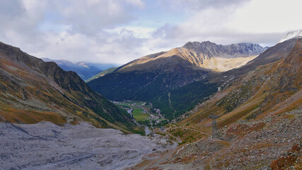 Beautiful view of upper Sulden valley, a popular tourist destination and ski resort in South Tyrol, Alps, Italy, in autumn season with the pillars of cableway and cloudy sky.