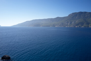 Calm sea with blue sky and mountains in the background. Picturesque seascape view. Vacation and rourism concept.