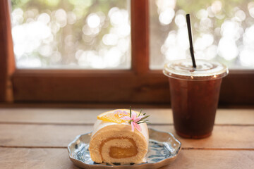 close up roll cake, homemade roll cake and ice coffee on wood table