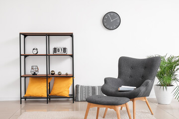 Stylish armchair and ottoman with rack in interior of room