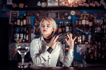 Expert woman bartending demonstrates his skills over the counter while standing near the bar counter in pub