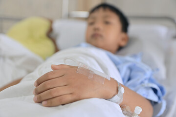 Obraz na płótnie Canvas Hand of an Asian boy plugged into a saline solution due to illness.