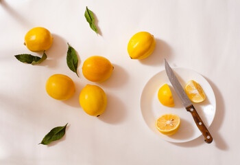 Fresh yellow lemons in a white plate on a white background. Half a lemon.