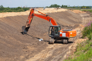 orange excavator works on road construction.