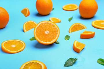 Juicy orange fruit with mint on color background
