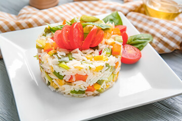 Plate of delicious rice salad with vegetables on light background