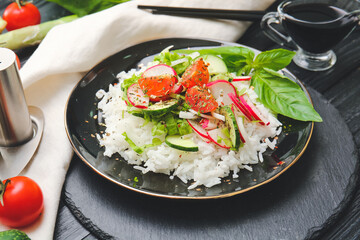 Plate of delicious rice salad with vegetables on dark wooden background