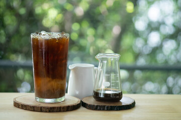 A glass of cold coffee and ice served with cream in small jar.