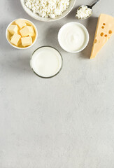 Natural, organic food most common dairy products are butter, cheese, milk, sour cream, cottage cheese flat lay on gray concrete background with copy space.
