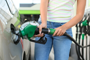 Woman filling up car tank at gas station, closeup
