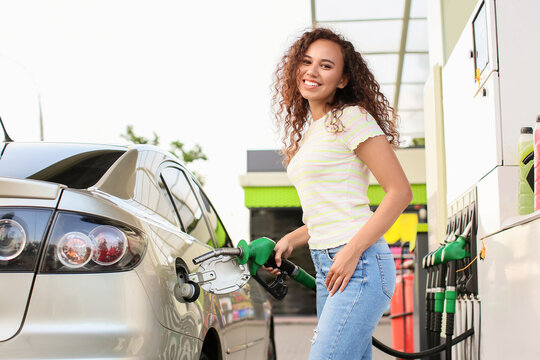 African-American Woman Filling Up Car Tank At Gas Station