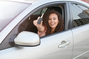 Young African-American woman with key sitting in new car