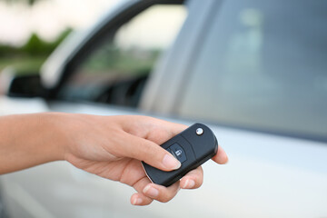 Young woman using car key fob outdoors, closeup