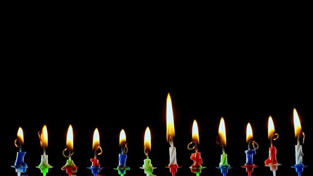 Burning out colored candles on a black background. Anniversary celebration concept.