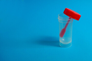 open plastic red container for collecting feces on a blue background side view . fecal analysis