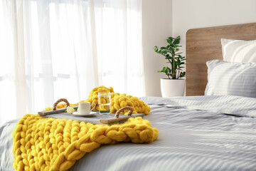 Knitted plaid with breakfast on bed at home