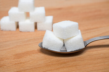 Sugar on a spoon on a wooden natural background. The concept of harm to health when sugar is consumed in large quantities