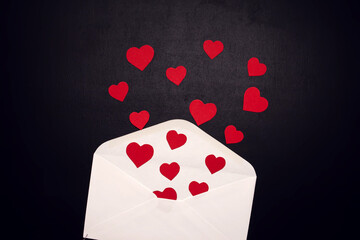 Envelope with hearts on the black background. Romance and holiday concept