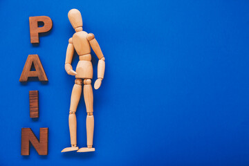 Wooden mannequin with word PAIN on color background