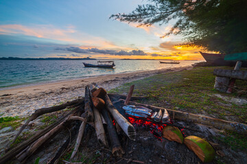 Fish bbq on tropical desert beach. Cooking barbecue with wood fire at sunset, colorful sky on sea, dramatic clouds, getting away, adventure in Indonesia Sumatra Banyak Islands