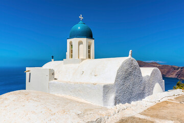 The blue dome and white walls of a traditional church on Skaros Rock, Santorini in summertime