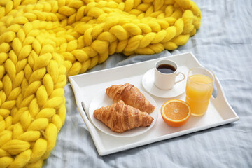 Tray with tasty breakfast on bed