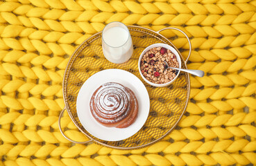 Tray with tasty breakfast on knitted plaid, top view