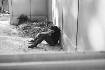 Depressed male junkie sitting outdoors. Concept of addiction