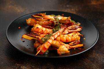 Grilled Tiger prawns skewers with garlic coriander and chili served on black plate