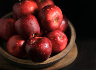 Still life with red apples in a bowl on a wooden table.