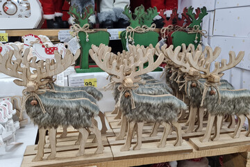 Christmas decorations, wooden decorative deers, sells on a shop counter. Festive shopping in mall.