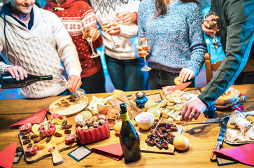 Side view of friends group tasting christmas sweets food and having fun at home drinking champagne...