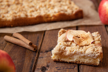 Kuchen mit Äpfeln als Füllung und Streusel auf einem braunen Tisch aus Holz in der Küche