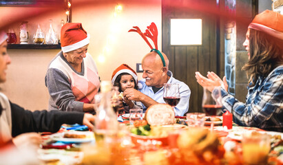 Large multi generation family having fun at christmas supper party - Winter holiday x mas concept with parents and children eating together opening gifts at home - Focus on grandpa and daugther hands