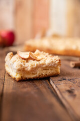 Kuchen mit Äpfeln als Füllung und Streusel auf einem braunen Tisch aus Holz in der Küche