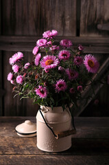 Still life with pink flowers in a can on a wooden table.