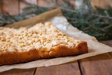 Kuchen mit Äpfeln als Füllung und Streusel auf einem braunen Tisch aus Holz in der Küche