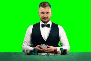 A croupier man sits at a table with chips and playing cards. isolate green screen. Casino concept, gambling.
