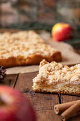 Kuchen mit Äpfeln als Füllung und Streusel auf einem braunen Tisch aus Holz in der Küche