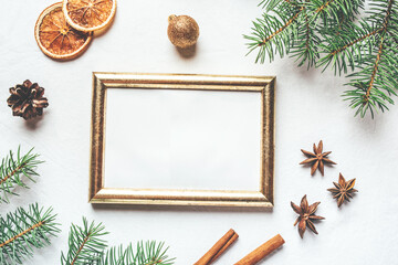 Greeting card for Christmas or New Yaer made of fir branche, spices and dried oranges and a cone with golden frame. Flat lay.