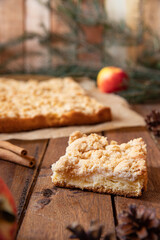 Kuchen mit Äpfeln als Füllung und Streusel auf einem braunen Tisch aus Holz in der Küche