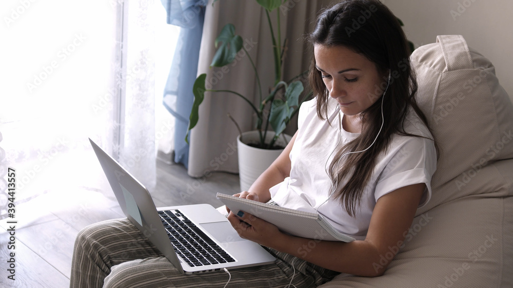 Wall mural young woman wears headset conference calling on laptop talks with online teacher studying, working f