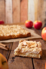 Kuchen mit Äpfeln als Füllung und Streusel auf einem braunen Tisch aus Holz in der Küche