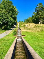 Flowing water from a concrete construction. A man made waterfall. Clear fresh water at a Swedish pond. Three levels of water. Nice view a sunny day outdoor. Jarfalla, Stockholm, Sweden.