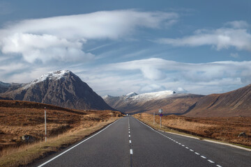 Road leading through the Scottish Highlands of Glen Coe, snowcapped mountains and valley. Scotland, United Kingdom