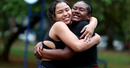 Diverse female friends hugging each other outside in park. Two girlfriends embrace - Powered by Adobe