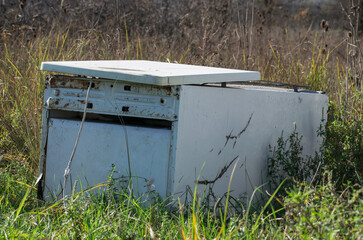 Old refrigerator abandoned in nature on a field. Old devices thrown in nature.