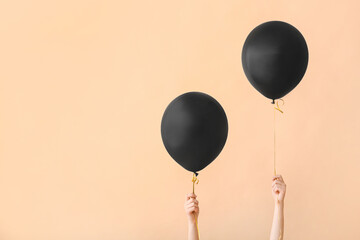 Female hands with black air balloons on color background © Pixel-Shot